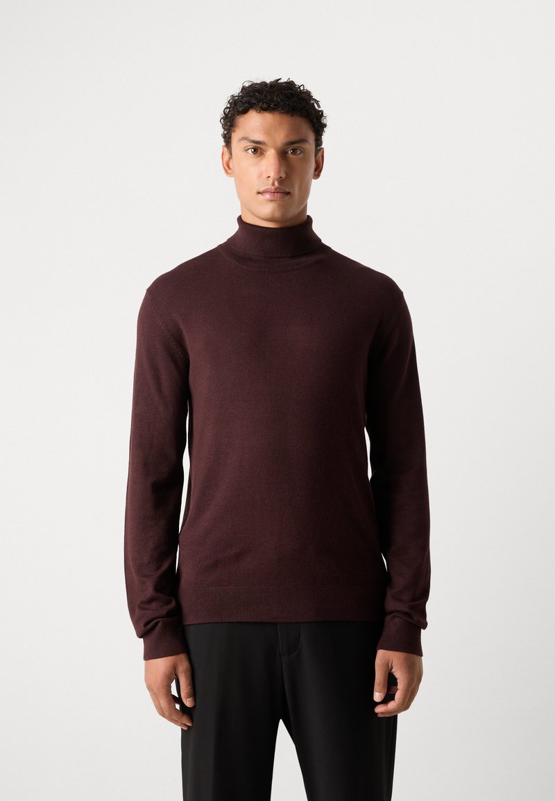 Bordeaux coltrui van zachte stof, aansluitend design, lange mouwen en geribde manchetten, gecombineerd met zwarte broek.