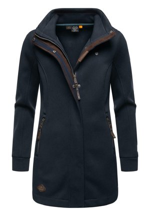 Cappotto lungo blu navy con alto colletto, chiusura a zip e dettagli in marrone. Presenta tasche laterali con zip e tessuto texture.
