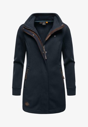 Tumši zils garais mētelis ar augstu apkakli, rāvējslēdzēja priekšpusi un brūniem akcentiem. Iekļauj rāvējslēdzēja sānu kabatas un teksturētu audumu.