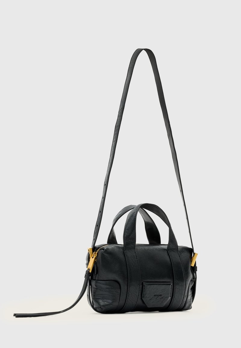 Petit sac à main en cuir noir avec deux petites poignées, une longue bandoulière réglable et des détails de fermeture éclair dorés.