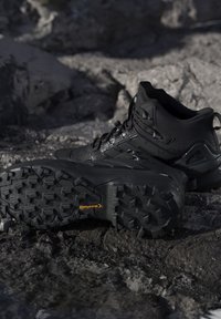 Zwarte wandelschoenen met robuuste Continental-zolen die rusten op rotsachtige grond buiten.