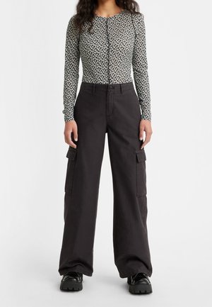 Zwarte cargobroek met zijzakken en een losse pasvorm, gecombineerd met een lange mouwen, bloempatroon, geknoopte top in zwart en wit.