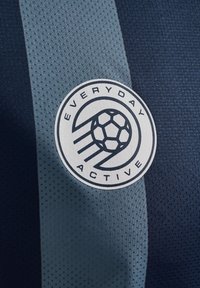 Marineblauwe en lichtblauwe mesh-stof met een circulair logo waarop een voetbal staat afgebeeld, met de tekst "EVERYDAY ACTIVE" in een moderne lettertype.