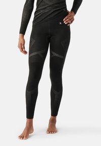 Leggings noirs au design ajusté, avec des motifs texturés et des rayures contrastées le long des jambes. Fabriqués en matériau flexible.