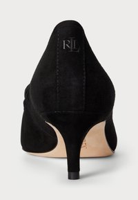 Fekete velúr magassarkú cipő hegyes orral; letisztult sziluettel, keskeny stiletto sarkámmal és dombornyomott logóval a hátsó részen.