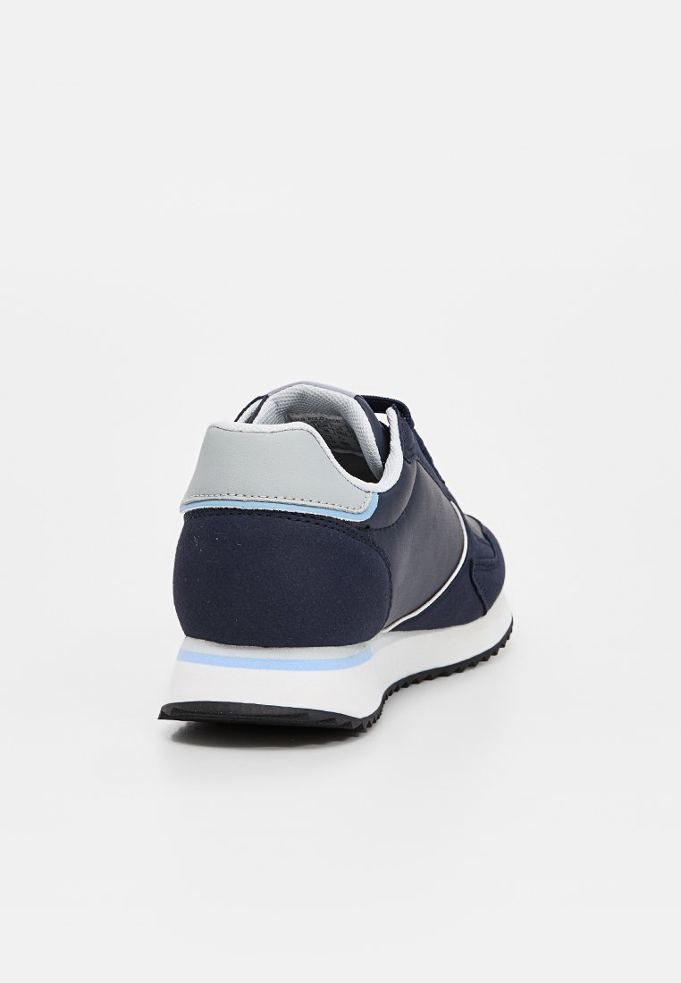 Zapatillas deportivas de color azul marino con un upper de tela texturizada, acentos en gris claro, un collar acolchado y una suela intermedia blanca con una franja azul.