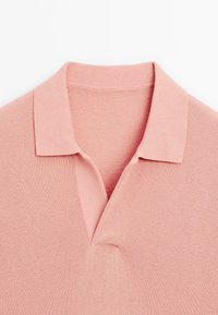 Rosa polo skjorta med en texturerad stickning, en kort krage och en öppen placketdesign. Tyget har ett slätt, andningsbart utseende.