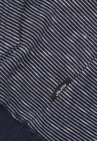 Close-up van donkerblauw en wit gestreepte brei stof met J&JOY merklabel genaaid in de naad.