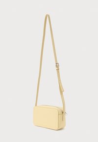 Világos sárga bőrből készült téglalap alakú válltáska, cipzáros záródással, állítható pánttal, sima textúrával és varrott részletekkel.