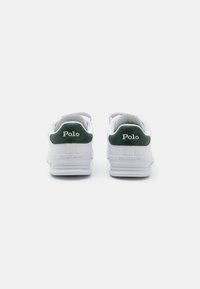 Weiße Sneakers mit grünen Lederspitzen an den Fersen. Mit "Polo"- und "Ralph Lauren"-Logos auf der Rückseite, Gummisohlen und strukturiertem Nähen.