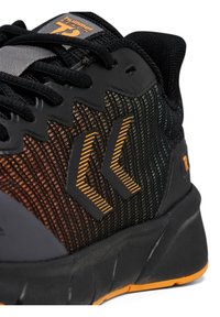 Svart och orange atletisk sko med en texturerad mesh-övre, med sicksackmönster och en tjock sula för stöd.