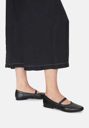 Černé kožené baleríny s vroubkovaným páskem, prošitými detaily a nízkým podpatkem, spárované s dlouhými černými šaty.