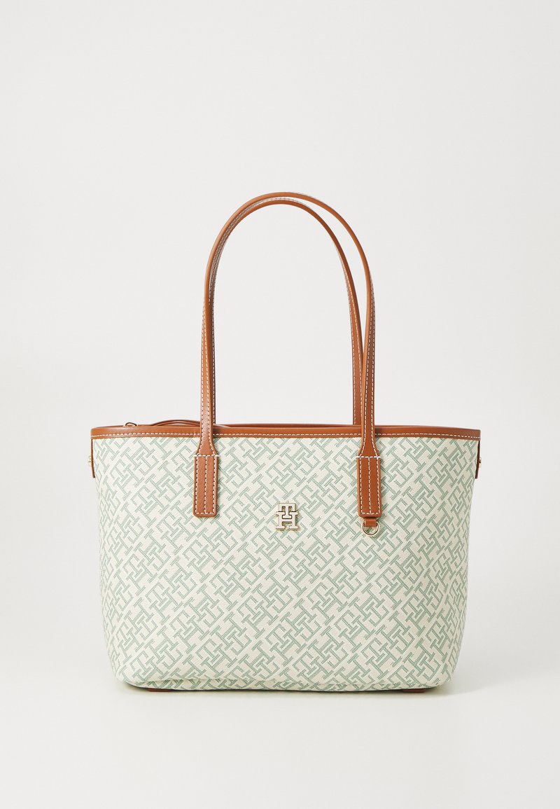 Tote taske med geometrisk mønster i mintgrøn og off-white, med brune læderhåndtag og detaljer, samt et guldfarvet emblem på forsiden.