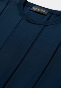 Top lavorato a maglia blu navy con scollatura rotonda, dettagli di cucitura verticale e morbida consistenza. Etichetta attaccata al collo con lettere dorate.