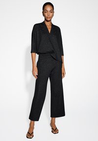 Zwart outfit met een losse, korte mouwen top en wijde broek, beide met glinsterende accenten voor een textuur uitstraling.