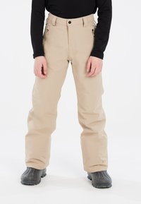 Pantaloni da neve impermeabili beige con un design a gamba dritta, tasche laterali con zip e chiusura con bottone in vita. Indossati con stivali neri.