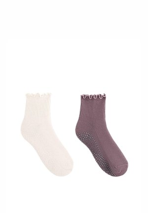 Par af ankellange gribetstrømper med flæsekant, én i creme og én i mauve, med skridsikre silikoneprikker under sålerne.