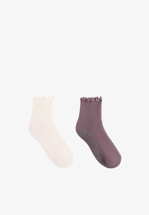 Par nogavic z oprijemom do gležnjev z volanastimi robovi, ena kremne in ena vijolične barve, z nedrsečimi silikonskimi pikami na podplatih.