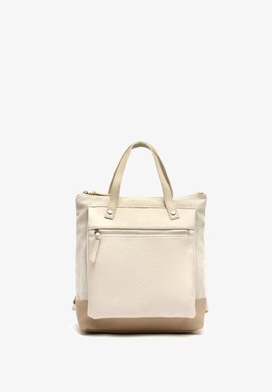 Beige en crèmekleurige draagtas met twee hengsels, een voorzak met ritssluiting en een rechthoekige vorm, geplaatst tegen een witte achtergrond.