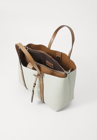 Handlenett i teksturert lys grønn materiale med brune lærhåndtak, med glidelås og brun innside. Merkbare sømdetaljer.