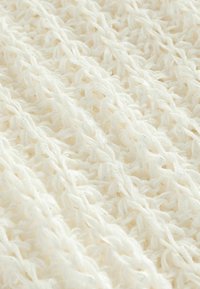 Tissu blanc tricoté avec un motif texturé, présentant des boucles complexes et une surface douce légèrement brillante. Idéal pour les vêtements ou accessoires.