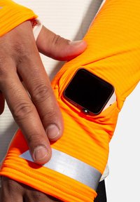 Orange atletisk ärmsleeve gjord av texturerat tyg, med en ficka för en smartklocka och en reflekterande silverdetalj.
