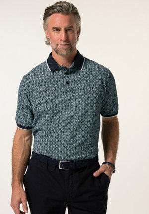 Polo a maniche corte in navy con un motivo geometrico, dettagli bianchi nel colletto e una vestibilità rilassata, abbinato a pantaloni scuri.