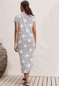 Maxi-jurk met een geometrisch zwart-wit patroon, korte mouwen, aansluitende silhouet, gemaakt van lichtgewicht stof, met een zij-split.