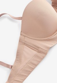 Beżowy, pikowany biustonosz z regulowanymi ramiączkami, gładkim materiałem, wsparciem na fiszbinach oraz zapięciem na haftki. Teksturowane detale po bokach.