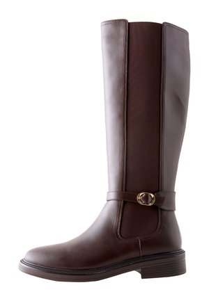 Augsti tumši brūni ādas jāšanas zābaki ar elastīgu sānu paneli un dekoratīvu zelta sprādzi ap potītes siksnu, plakanām papēžiem un apaļu purngalu.