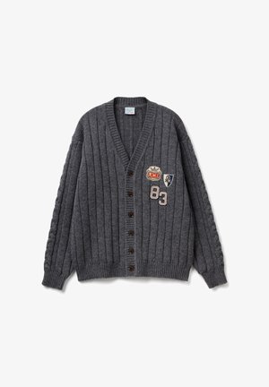 Šedý žebrovaný kardigan s výstřihem do V, hnědými knoflíky a vyšívanými nášivkami zobrazujícími korunu a číslo 83. Texturovaná pletená látka.