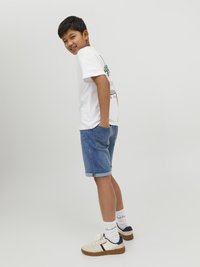 Vitt t-shirt med grafisk tryck, denim shorts, vita sneakers med marinblå detaljer och vita strumpor. Avslappnad passform och uppvikta kanter.