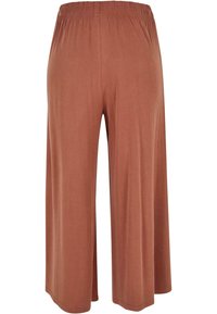 Pantalon à jambes larges en tissu doux de couleur rouille avec une ceinture élastique. Caractéristiques : une texture lisse et un design minimaliste sans motifs.