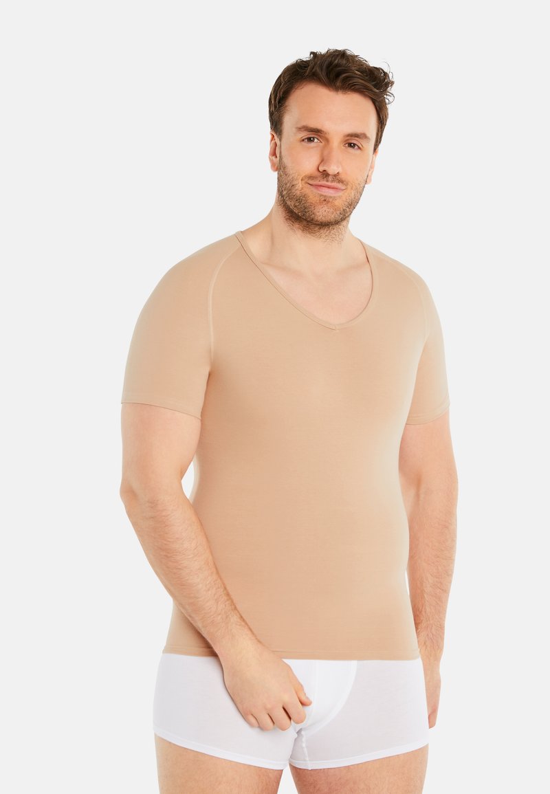 Beige short-sleeve V-neck tee with a smooth texture, fitted design, and seam detailing, worn over white underwear.