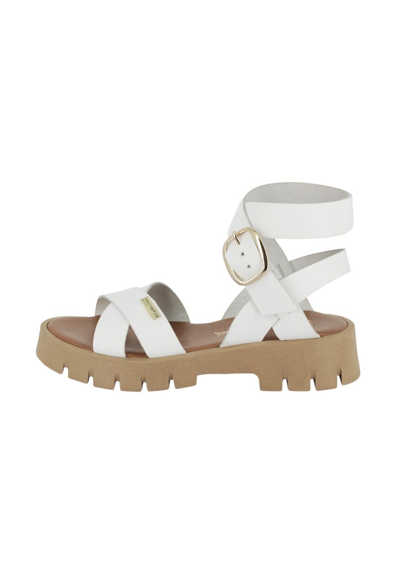 Sandal in pelle bianca con accentuazione a fibbia, cinturini incrociati e una suola spessa in gomma marrone con un motivo rigato per una presa migliore.