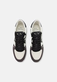 Sorte og hvite sneakers med et teksturert mesh-overdel, semskede detaljer og gummisåle. Har svarte lisser og logo-detaljer på tungen.