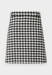 Svartvit houndstooth-mönstrad väska i texturerat material, med en strukturerad form och detaljer i guldfärgad metall.