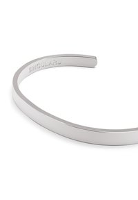 Silverfärgad metallarmband med ett slätt, smalt band och en subtil graverad logotyp på insidan, med en minimalistic design.