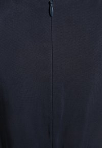 Navy blue dress featuring a textured fabric with a seam down the center and a zipper closure at the back. Simple and streamlined design.