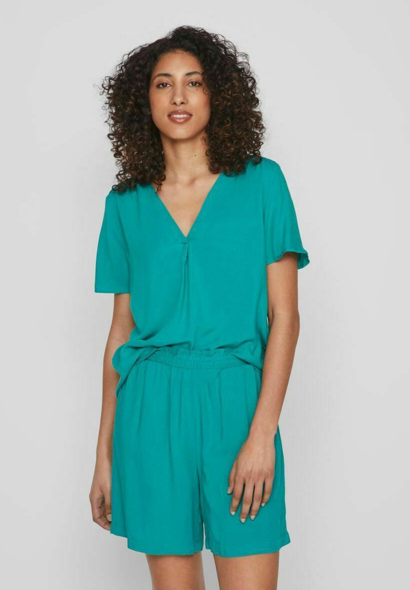 Conjunto de dos piezas en color verde azulado que incluye una blusa de manga corta con escote en V y pantalones cortos con cintura elástica. Fabricado en una tela ligera y suave, con un ajuste casual.