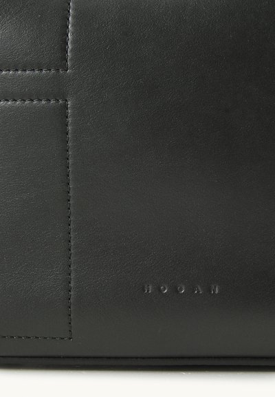 Geantă de mână din piele neagră, cu o textură netedă, design rectangular, cusături vizibile și numele mărcii embosat.