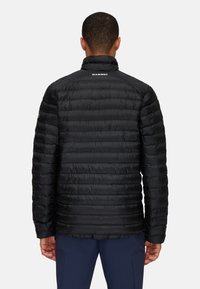 Sort isoleret pufferjakke med quiltet design, høj krave og glat tekstur. Har logo på ryggen. Velegnet til udendørs brug.
