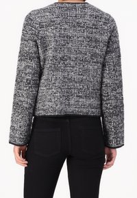 Maglione corto a maniche lunghe in bianco e nero con trama, con scollatura rotonda e vestibilità strutturata, abbinato a pantaloni neri.