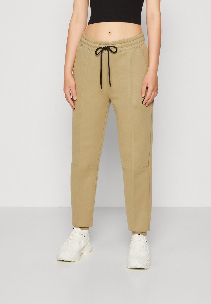 Beiga joggerbyxor med elastisk midja och svart dragsko, med sidfickor och en avsmalnande bendesign. Mjuk bomullsblandning.