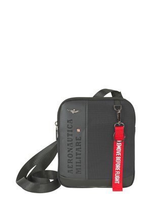 Borsa a tracolla nera con scritta "AERONAUTICA MILITARE", emblema a forma di ala in metallo e portachiavi rosso con scritto "REMOVE BEFORE FLIGHT".
