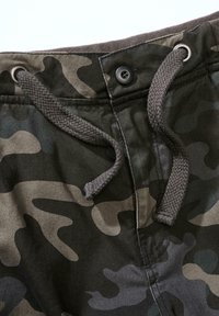 Karinės kelnės žalių ir pilkų atspalvių, su raištelio uždarymu, metaliniais mygtukais ir tekstūruota medžiaga.