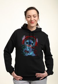 Felpa nera con cappuccio che presenta un grafico di un personaggio dei cartoni animati con cuffie, che tiene un controller di gioco, accentuato da vivaci effetti digitali.
