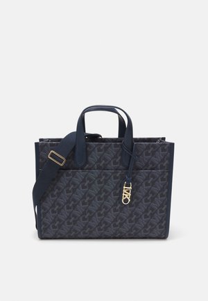 Mørkeblå stof tote bag med præget logo-mønster, dobbelte top-håndtag og en aftagelig skulderrem med guldfarvede hardware-detaljer.