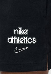 Μαύρο αθλητικό σορτς με ανάγλυφο λευκό λογότυπο "nike athletics" και ασημένιο σήμα Nike Swoosh στο κάτω μέρος της πλευράς. Μαλακή υφή υφάσματος.