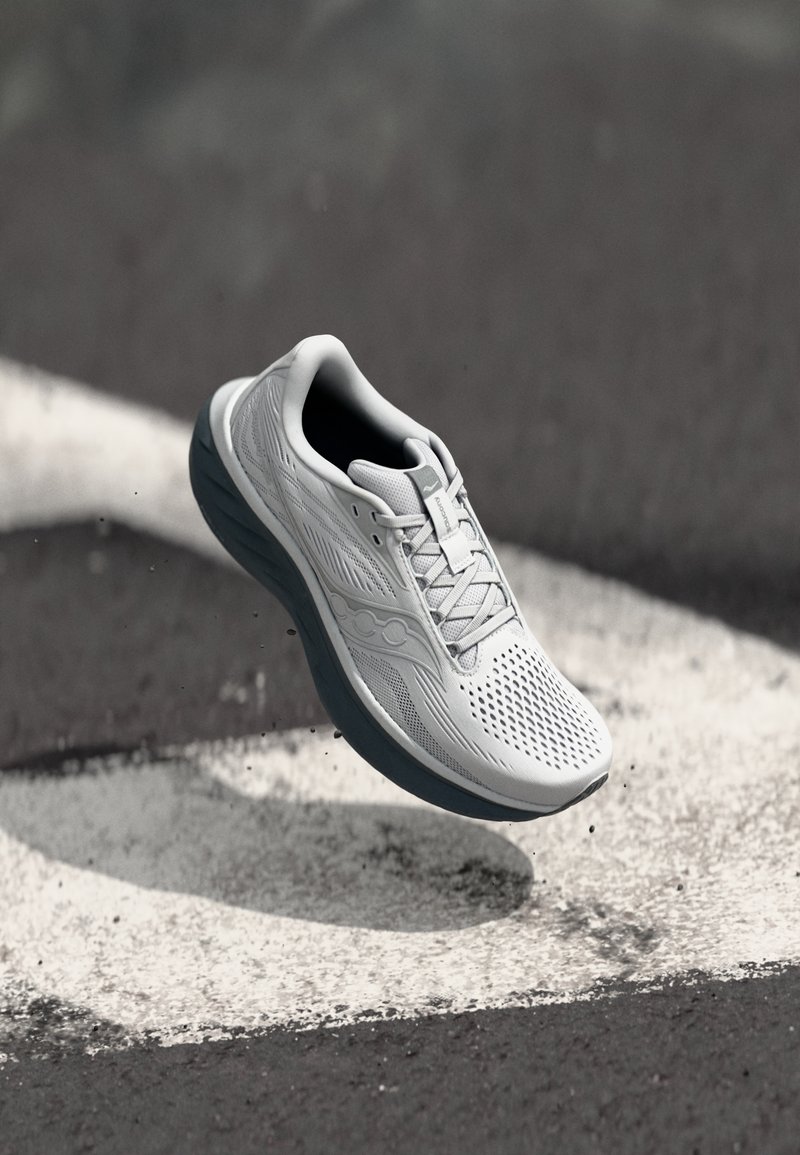 Chaussure de course légère en blanc et gris, dotée d'un dessus en maille avec des perforations, d'une semelle rembourrée et d'un design épuré.